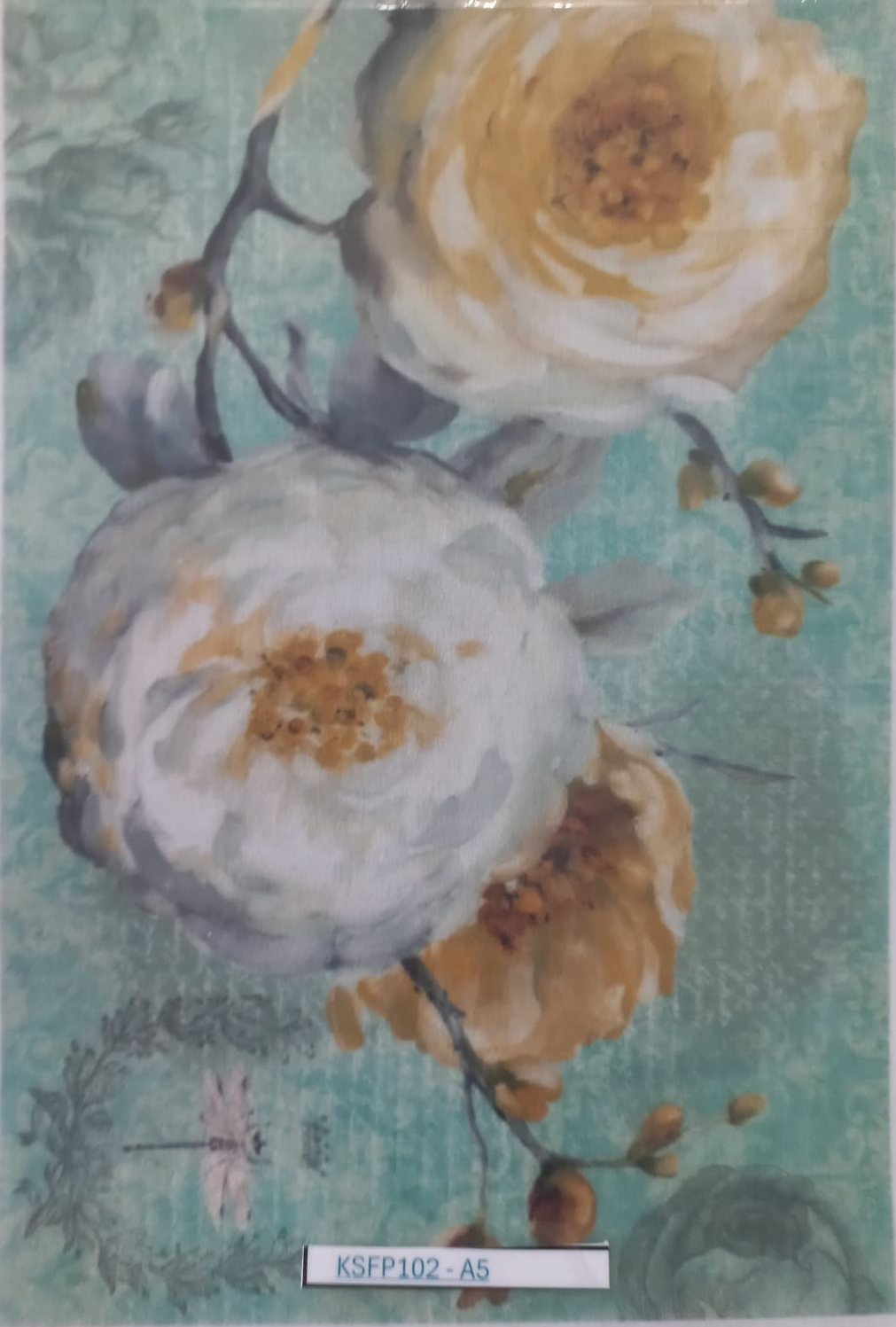A floral art print or card featuring large cream and white flowers with yellow centers on a textured light teal background, photographed inside a clear plastic sleeve. A small label at the bottom reads KSF102-A5.