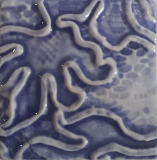 A close-up of a glossy ceramic tile featuring an abstract, organic wavy pattern in shades of blue and white.