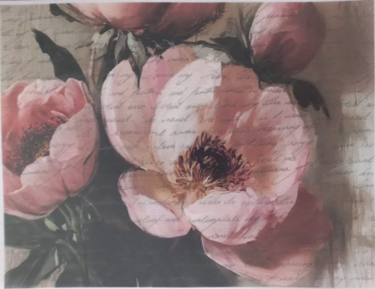 A sheet of decorative paper featuring a watercolor-style floral print of pink peonies over a vintage cursive script background, photographed flat with a protective plastic sleeve.