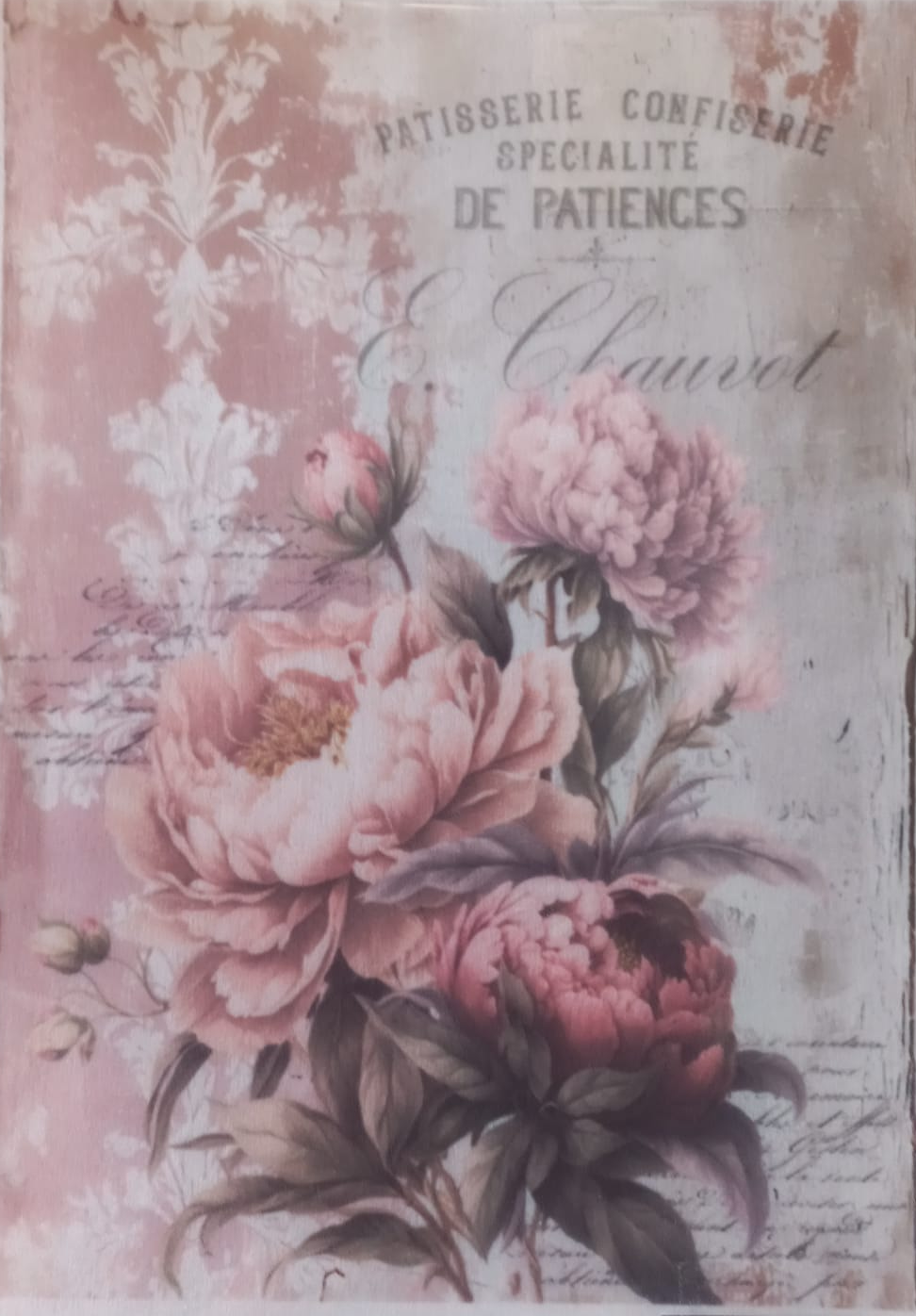 A rectangular decorative print or card featuring a vintage-style floral design with large pink peonies, botanical motifs, and French text including 'PATISBERGIE CONFISERIE DE PATIENS & Chaulrot'. The print is photographed inside a clear plastic sleeve against a white background.