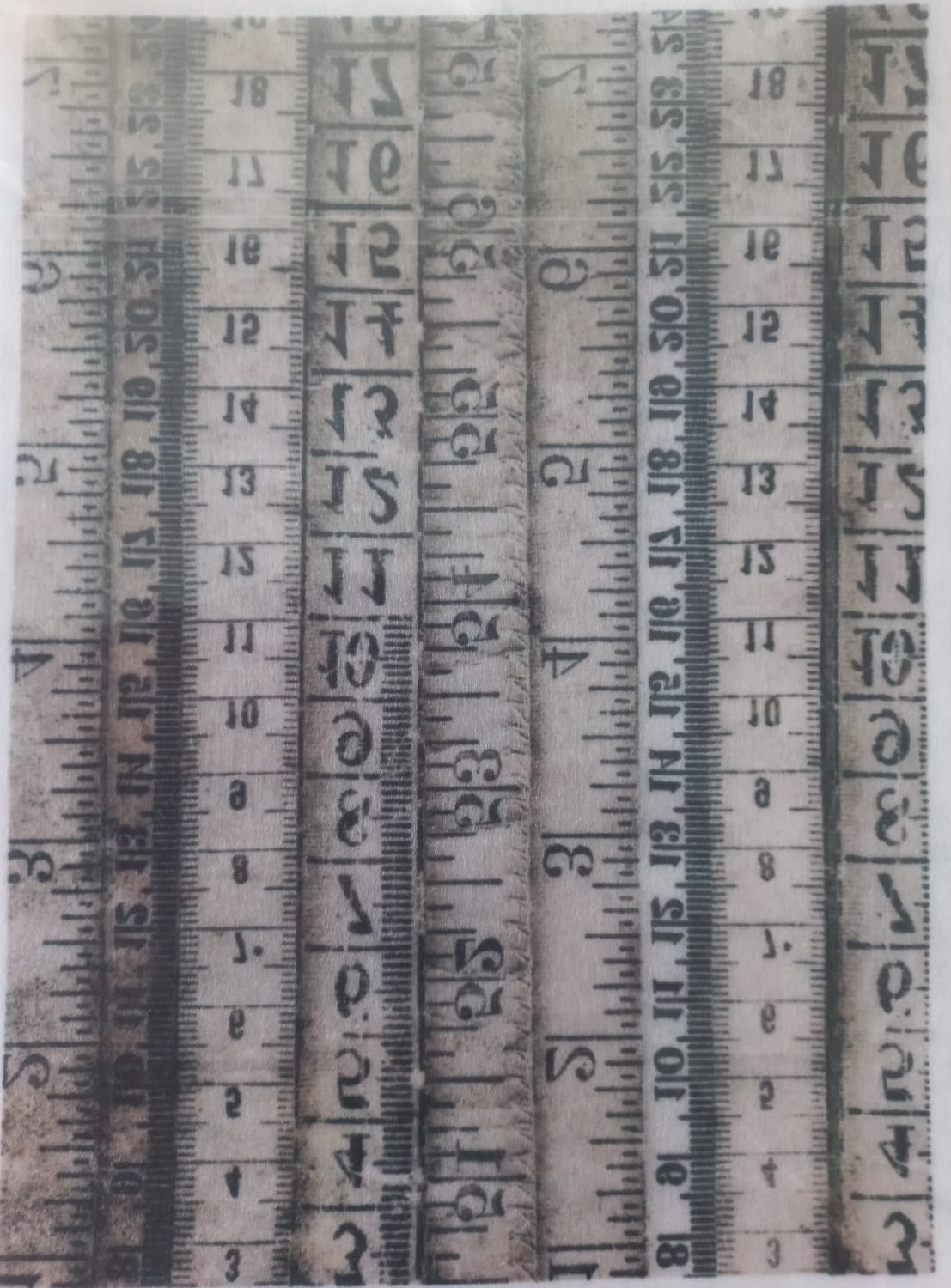 A rectangular printed design featuring multiple vertical vintage tape measure scales in black and gray on a distressed off-white background, photographed inside a clear plastic sleeve.