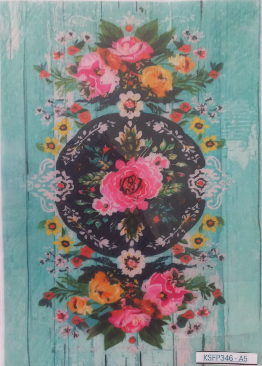 A rectangular printed card or art print featuring a turquoise wood-plank background with a central black oval containing pink and orange flowers, surrounded by additional floral clusters. The print is photographed inside a clear plastic sleeve, with a small label at the bottom reading KSFP346-A5.