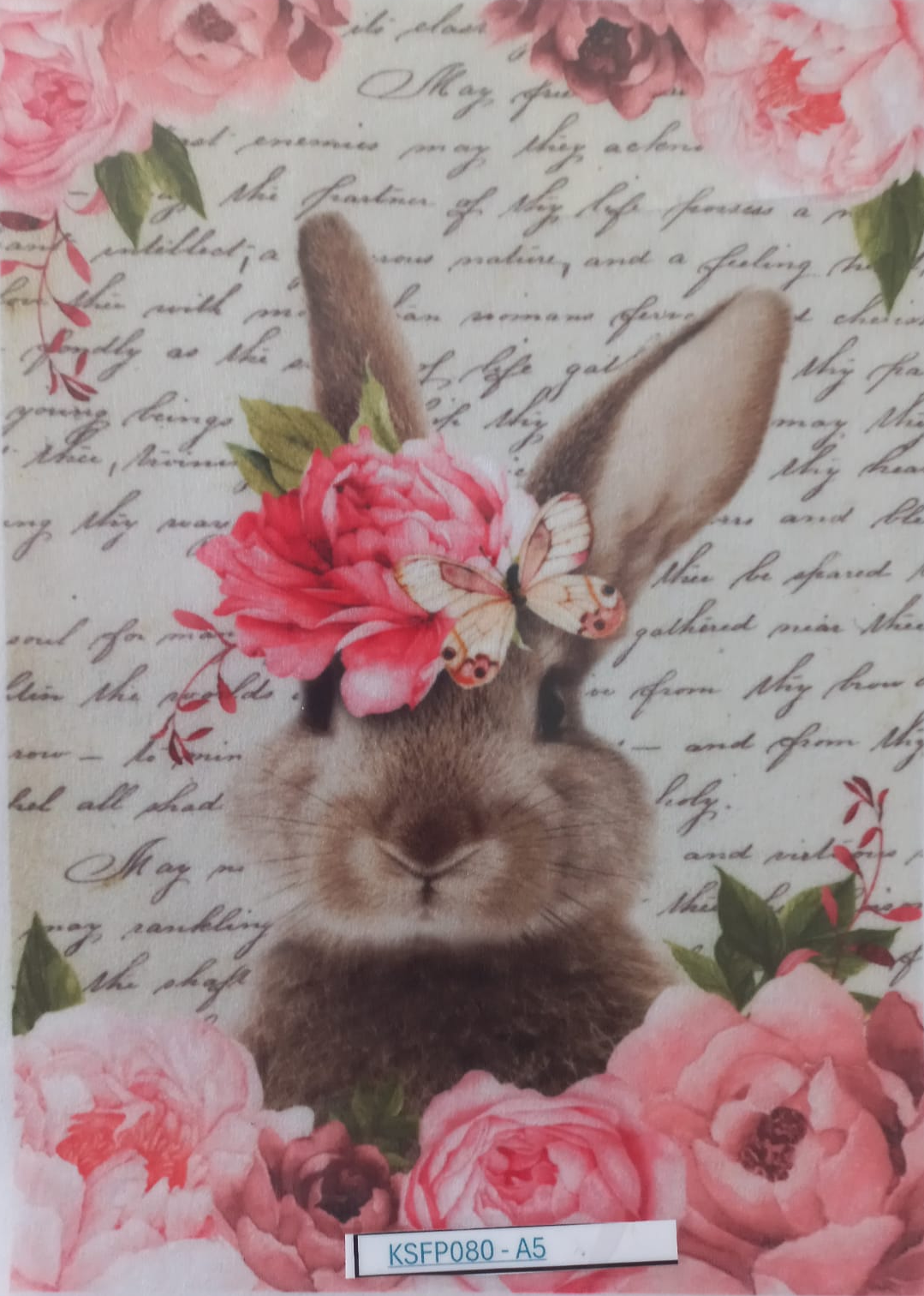 A decorative printed card or sticker featuring a gray-brown rabbit centered on a vintage-style cream background with cursive script, surrounded by large pink roses and green leaves. A small butterfly graphic appears near the rabbit's head, and a white label at the bottom reads KSFP080-A5.