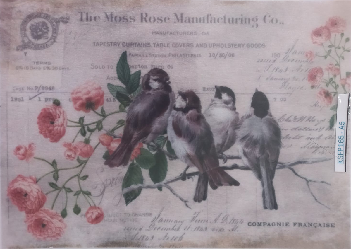 A vintage-style printed textile or craft paper design featuring four birds perched on a branch among pink roses, with printed text including 'The Moss Rose Manufacturing Co.' and 'Compagnie Francaise.