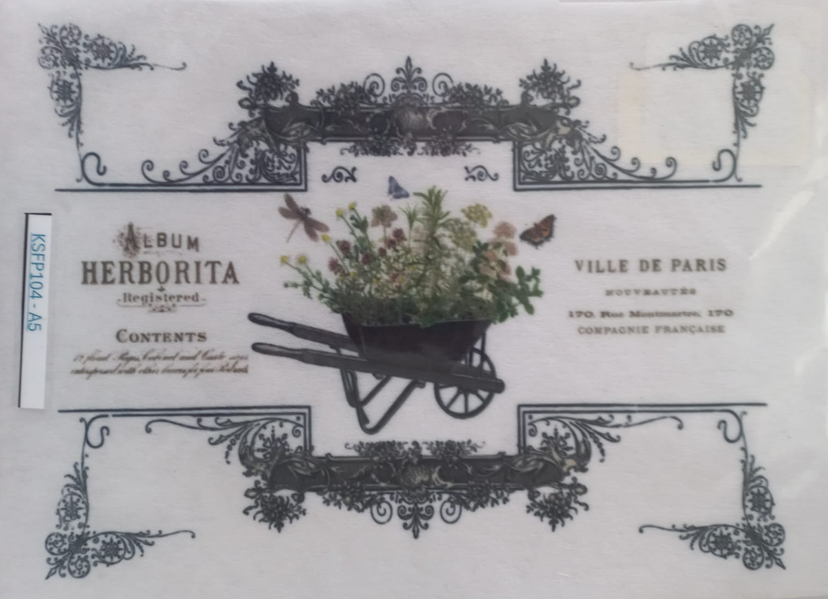 A vintage-style printed card or label inside a clear plastic sleeve, featuring ornate black decorative borders, French text including 'Album Herborita' and 'Ville de Paris,' and a central illustration of a wheelbarrow filled with flowers and greenery.