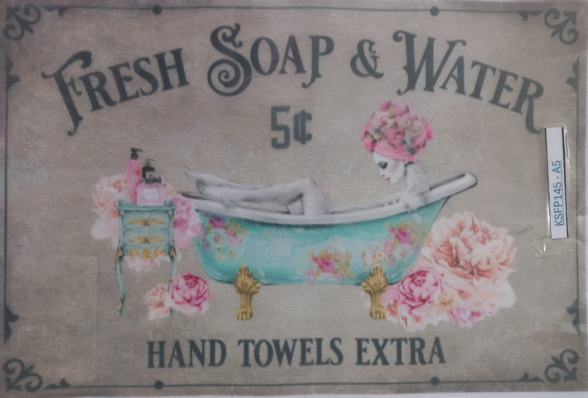 A vintage-style hand towel label reading 'Fresh Soap & Water 5¢' with an illustration of a woman relaxing in a floral bathtub, surrounded by roses, and the text 'Hand Towels Extra.'.